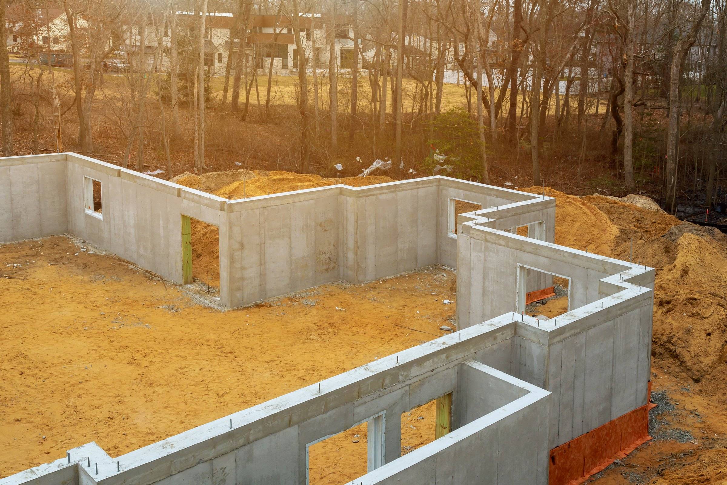Poured concrete foundation walls of a house under construction, with openings for basement windows